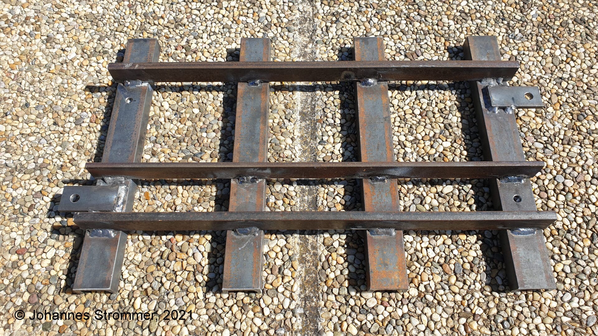 Dreischienengleis für die Spurweiten 127 mm (5 Zoll) und 184 mm (7 ¼ Zoll). Die Schienen bestehen aus einem Flachstahl 30 x 10 (7,25 Zoll) bzw. 30 x 6 (5 Zoll) und die Schwellen aus einem U-Stahl 40 x 20 x 5.